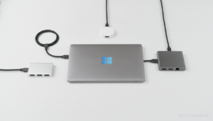 A flat lay photo on a clean white desk showing a selection of compact USB-C hub and docking station devices with multiple ...